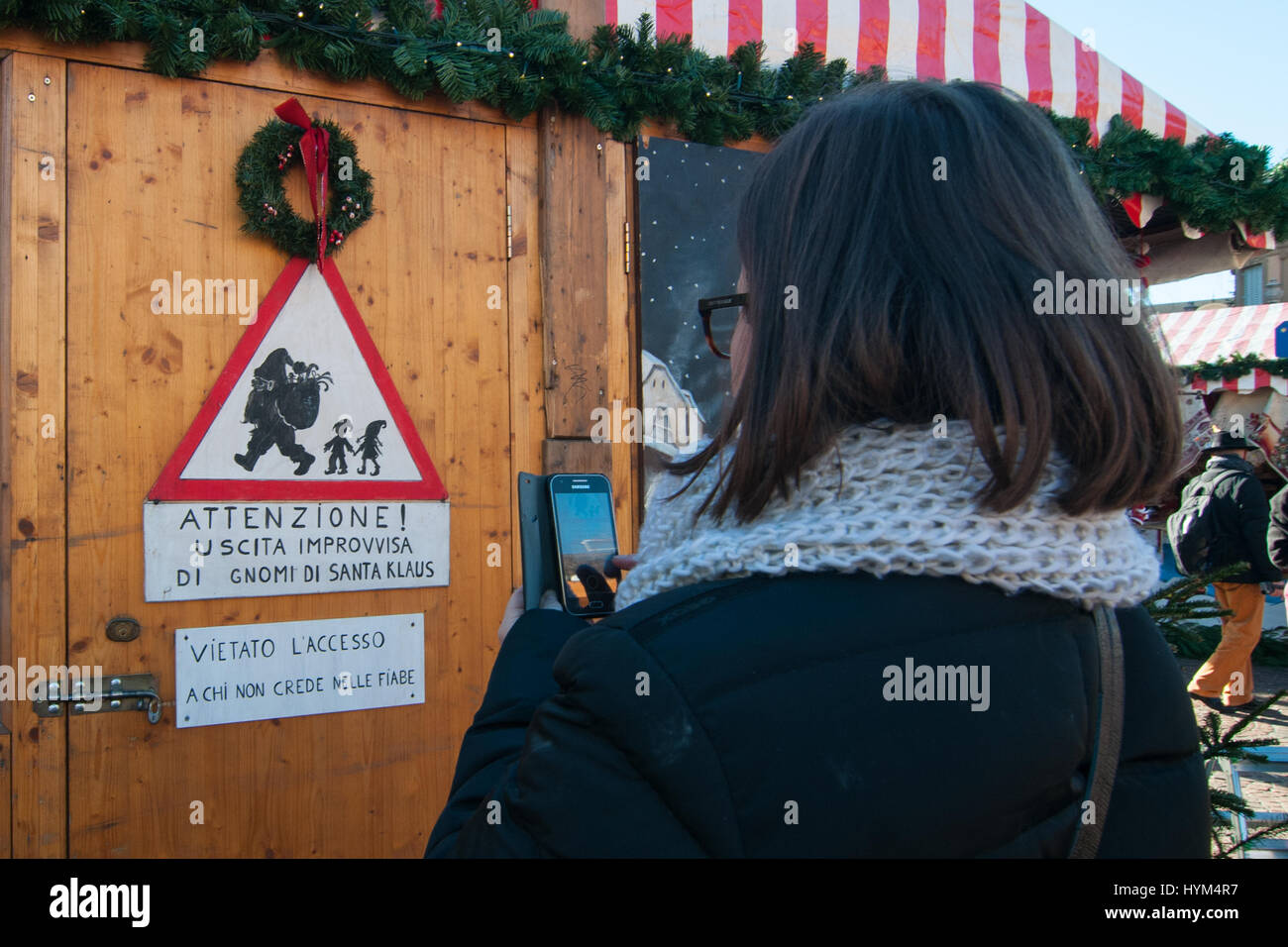 Una donna scatta una foto con un segno che indica all' avviso, improvvisa uscita di Santa gnomi dell' presso il tradizionale mercatino di Natale di Bolzano, in Italia. Foto Stock