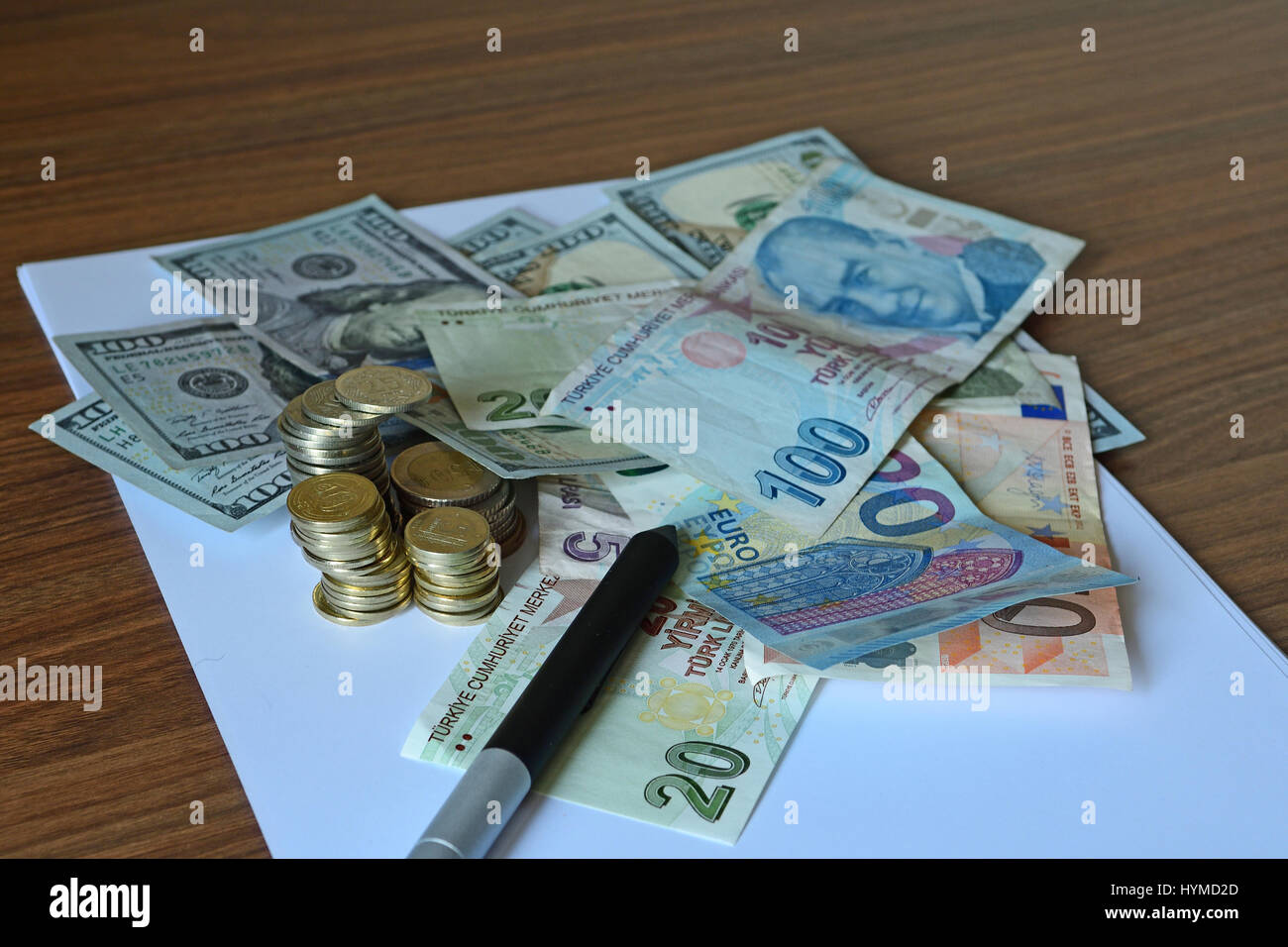 Monete di carta, Lire, dollari, euro lungo con monete e penna su bianco nota carta su una scrivania in legno Foto Stock