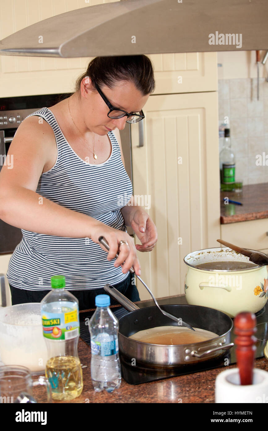 Donna polacca età 37 rendendo crepes sul suo fornello da cucina. Zawady Polonia centrale Europa Foto Stock