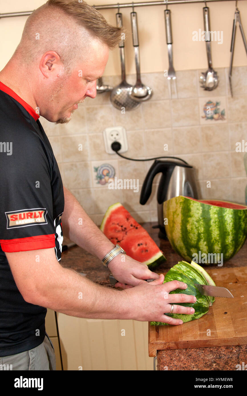 Uomo di tranciatura di un cocomero nella sua cucina. L'uomo 41 anni. Zawady Polonia centrale Europa Foto Stock