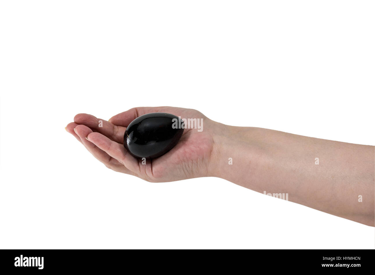 Senior donna di mano che regge un uovo nero isolato su sfondo bianco Foto Stock