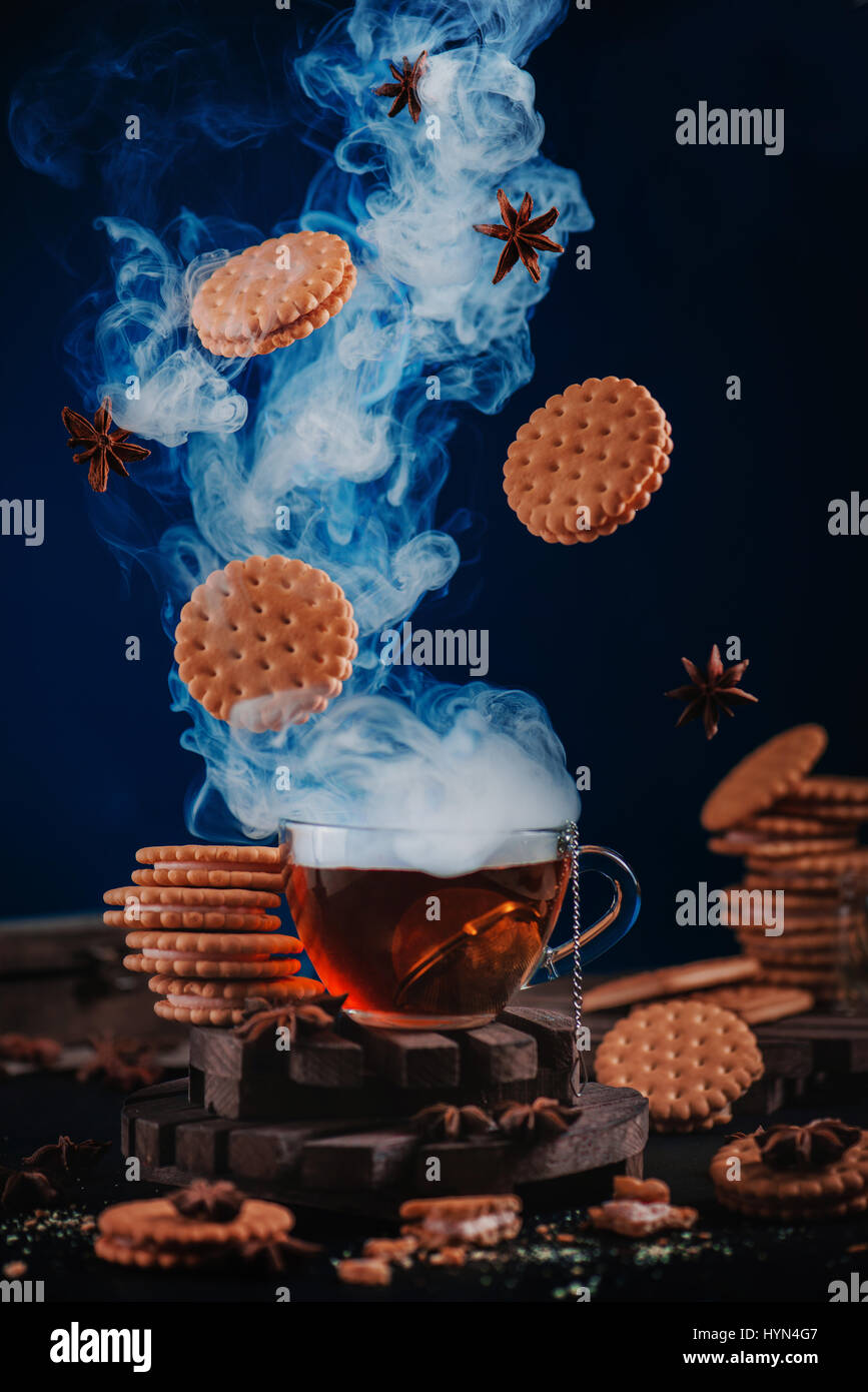 Fumante tazza di tè con biscotti volanti e spezie Foto Stock