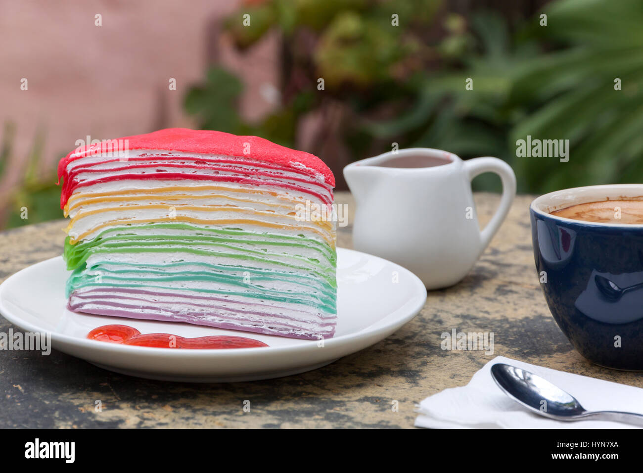 Torta arricciato arcobaleno e caldo di caffè espresso nel lato giardino home. arricciato torta con salsa di fragole Foto Stock