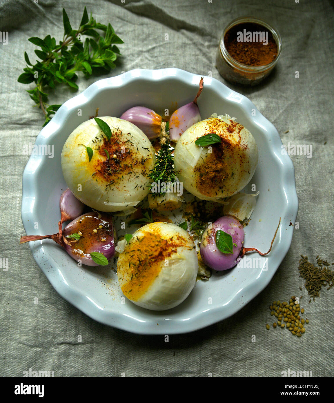 Grandi cipolle bianche, gli scalogni e l'aglio bianco in teglia con erbe e spezie su tavola con tela panno in luce morbida Foto Stock
