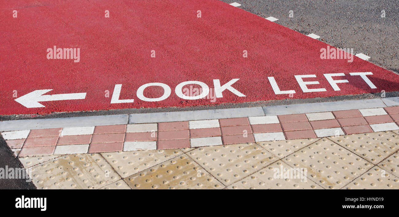 Dipinto di guardare a sinistra cartello stradale e la freccia su una superficie strutturata attraversamento pedonale in Buckingham Foto Stock