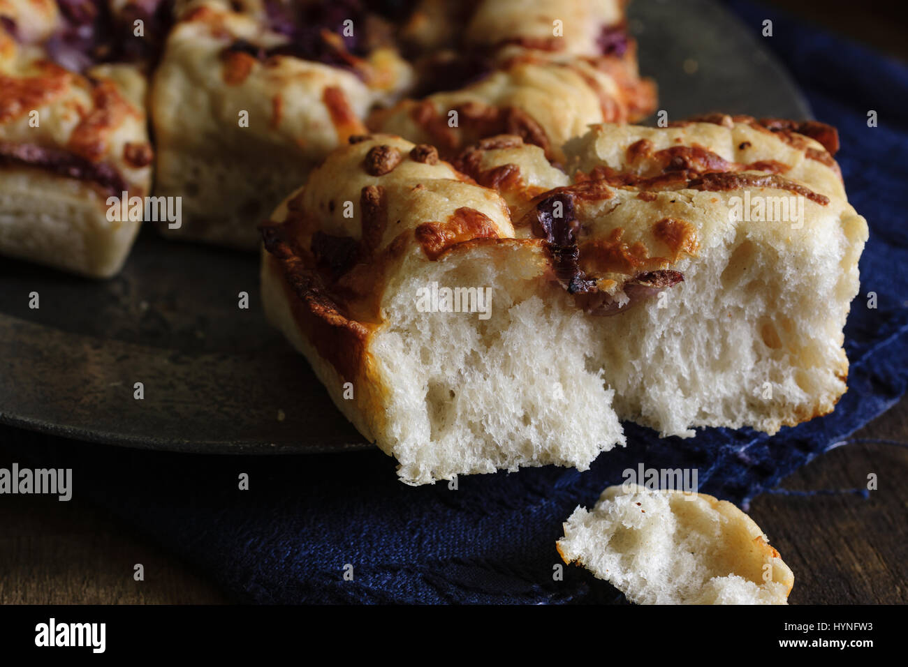 Pane Focaccia guarnita con caramellato cipolla rossa e mozzarella su una piastra in peltro shot con bassa illuminazione tasto Foto Stock