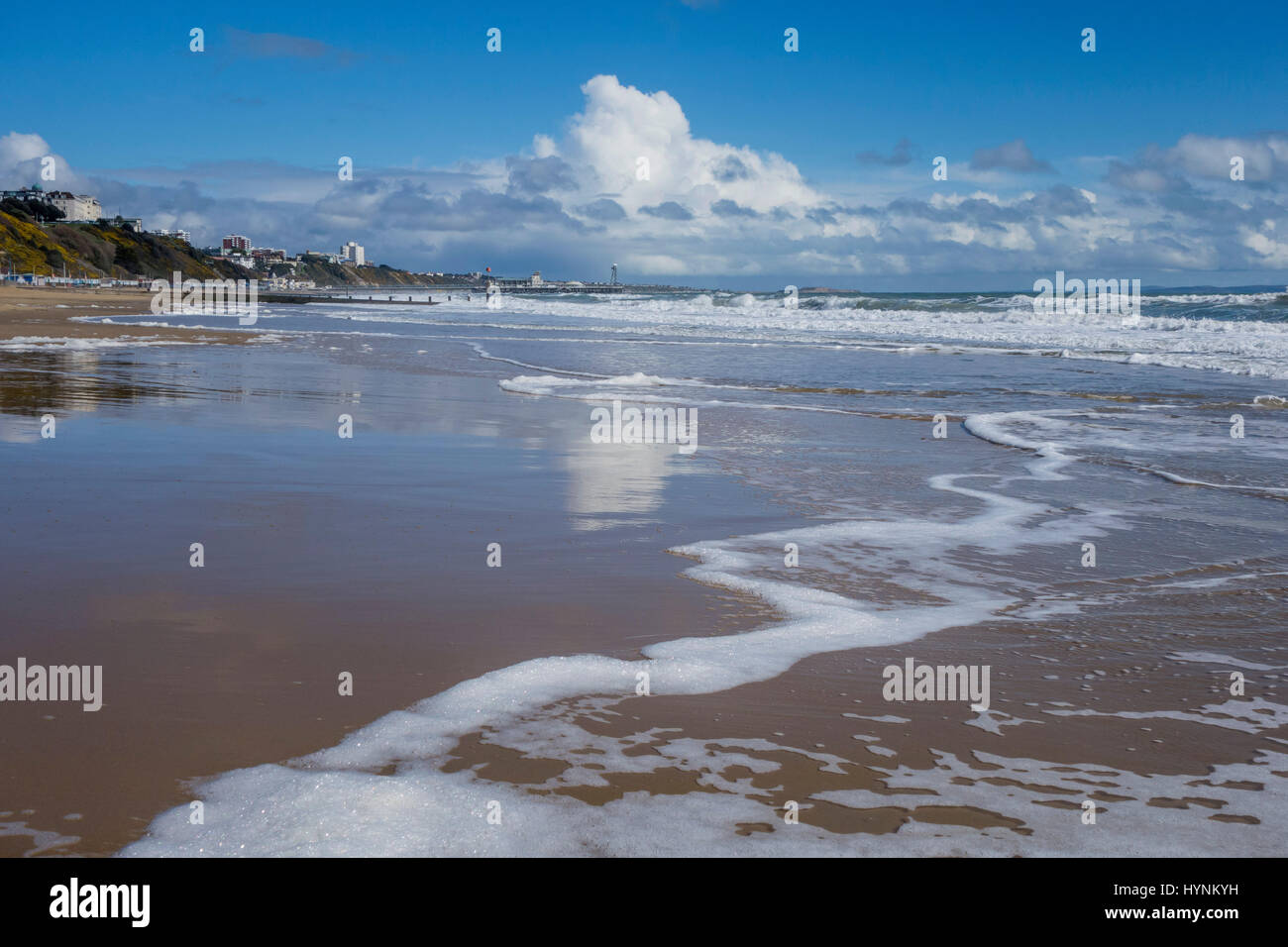 Bournemouth Beach Mostra bordo del mare con marea sulla sabbia, lasciando una riflessione di nuvole e cielo blu sul bagnato riva sabbiosa. Foto Stock