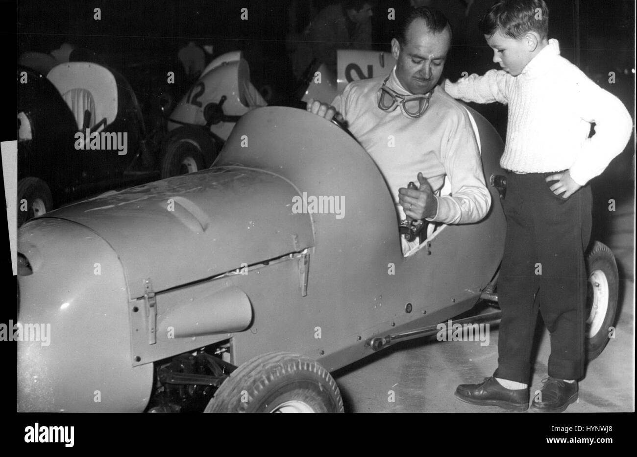 Apr. 04, 1958 - Racing ace e appassionato di giovanile: il primo test viene eseguito di Micromits, il midget racing cars, ha avuto luogo presso il Palais des Sports, Parigi, oggi. La prima gara si terrà il 23 aprile. Mostra fotografica di Maurice Trintignant, il famoso corridore francese, per spiegare il funzionamento del midget auto per un giovane appassionato. (Credito Immagine: © Keystone Press Agency/Keystone USA via ZUMAPRESS.com) Foto Stock