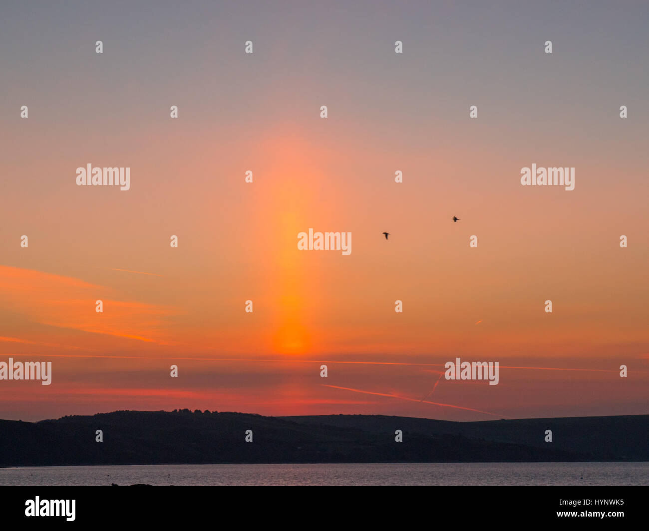 Weymouth Dorset, Regno Unito. Il 6 aprile 2017. Sunrise vibranti colori con un insolito striatura verticale sopra la Baia di Weymouth guardando verso il Giurassico orientale costiera. © DTNews/Alamy Live News Foto Stock