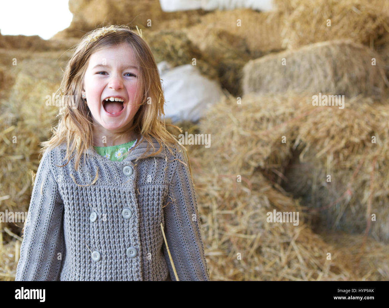 Close up ritratto di una giovane ragazza ridere con paglia e fieno in capelli in fattoria Foto Stock