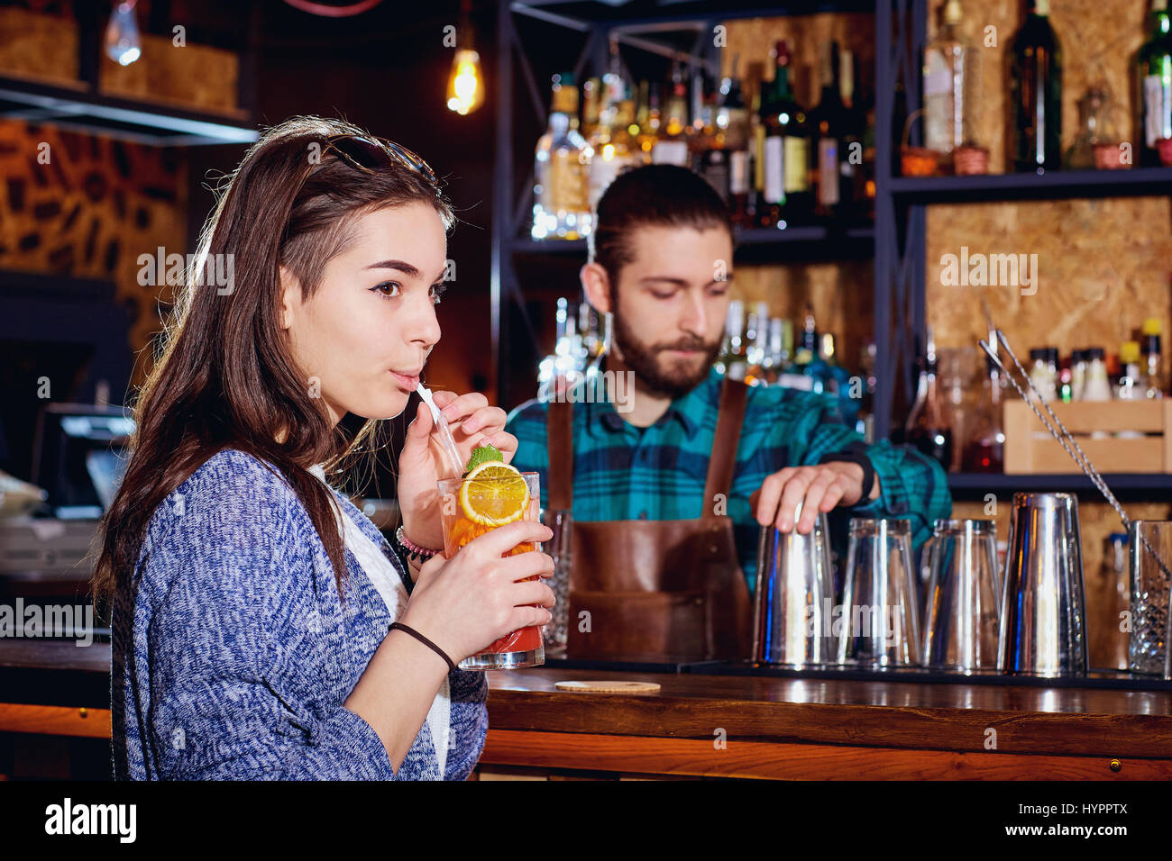 Ragazza beve un cocktail da paglia nel bar su barman lo sfondo Foto Stock