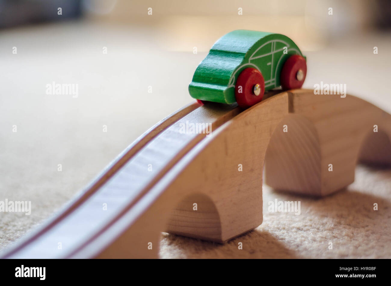 Un giocattolo auto in legno sulla parte superiore di un giocattolo di ponte di legno. La macchina corre lungo una via con scanalature di guida si tratta di ruote. Foto Stock