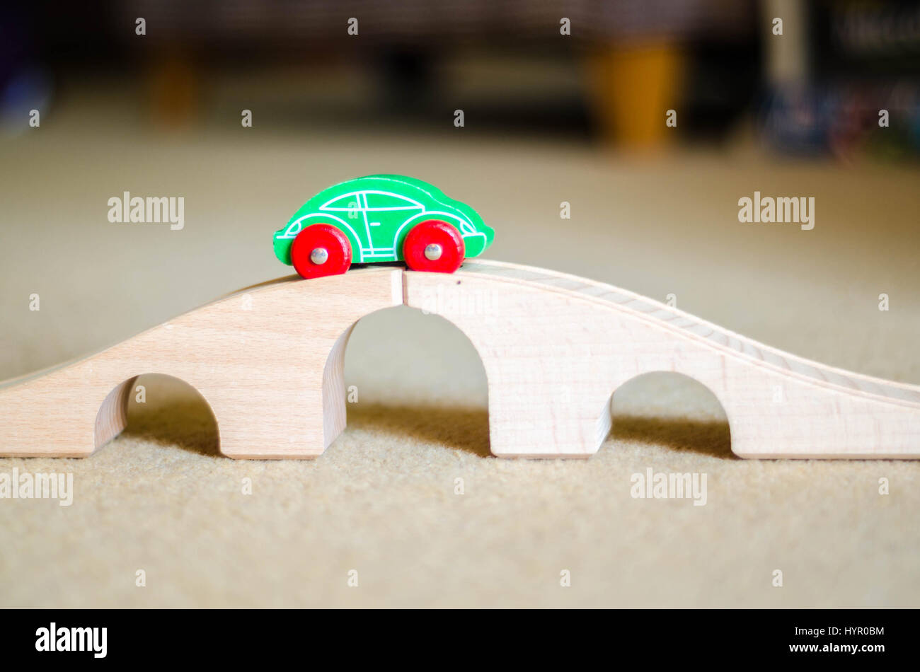 Un giocattolo auto in legno sulla parte superiore di un giocattolo di ponte di legno. La macchina corre lungo una via con scanalature di guida si tratta di ruote. Foto Stock