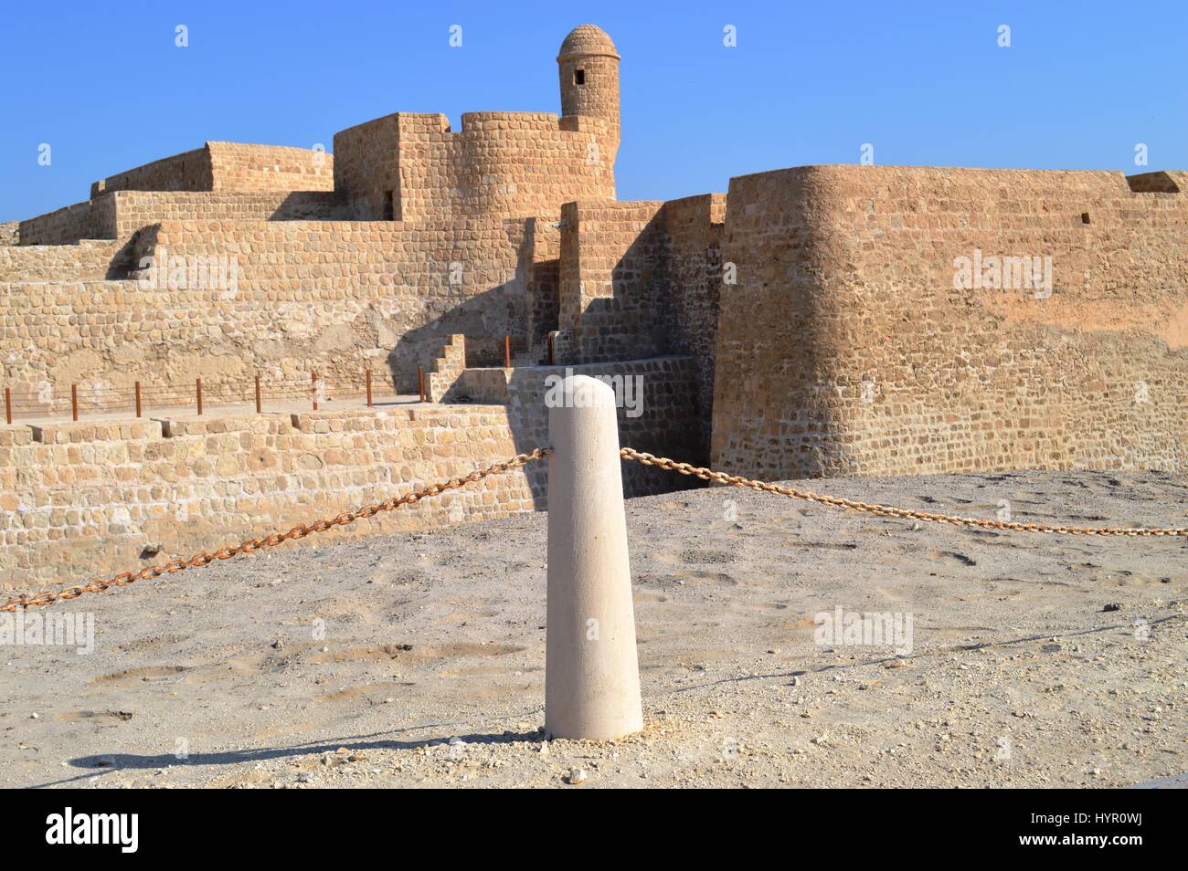 Un bollard allineato alla torre di avvistamento del Bahrain Fort at Al Qalah, Bahrein, in Medio Oriente. Foto Stock