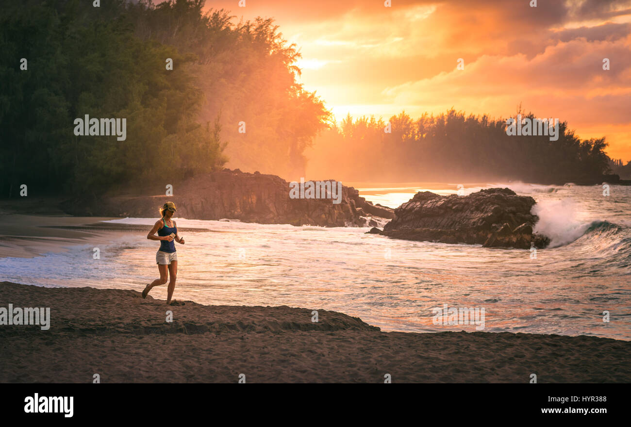 Un pareggiatore femmina corre lungo la spiaggia alle Hawaii durante il sunrise. Foto Stock