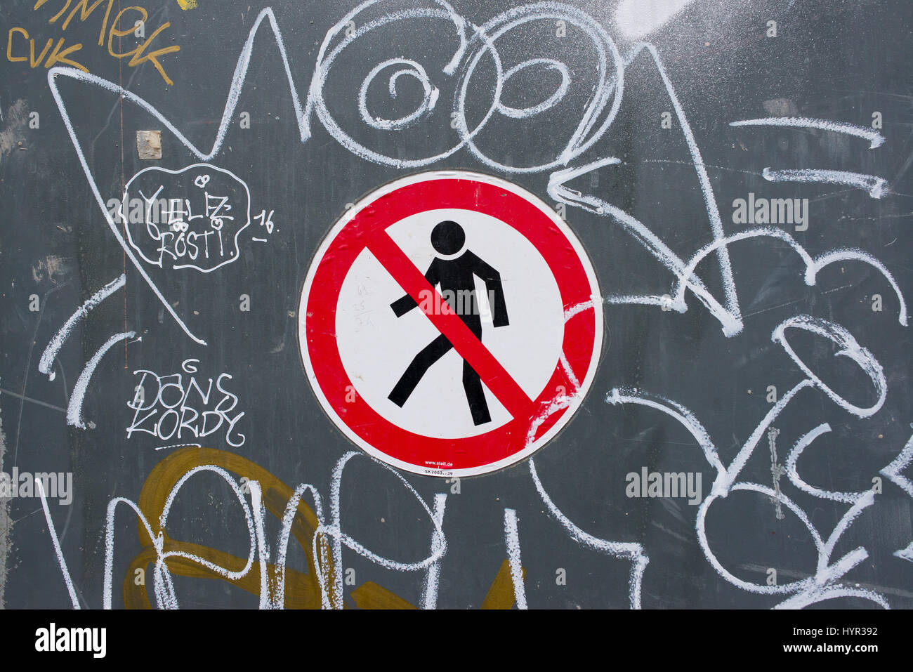 No attraversamento pedonale segno su un muro grigio con gli scarabocchi e graffiti Foto Stock