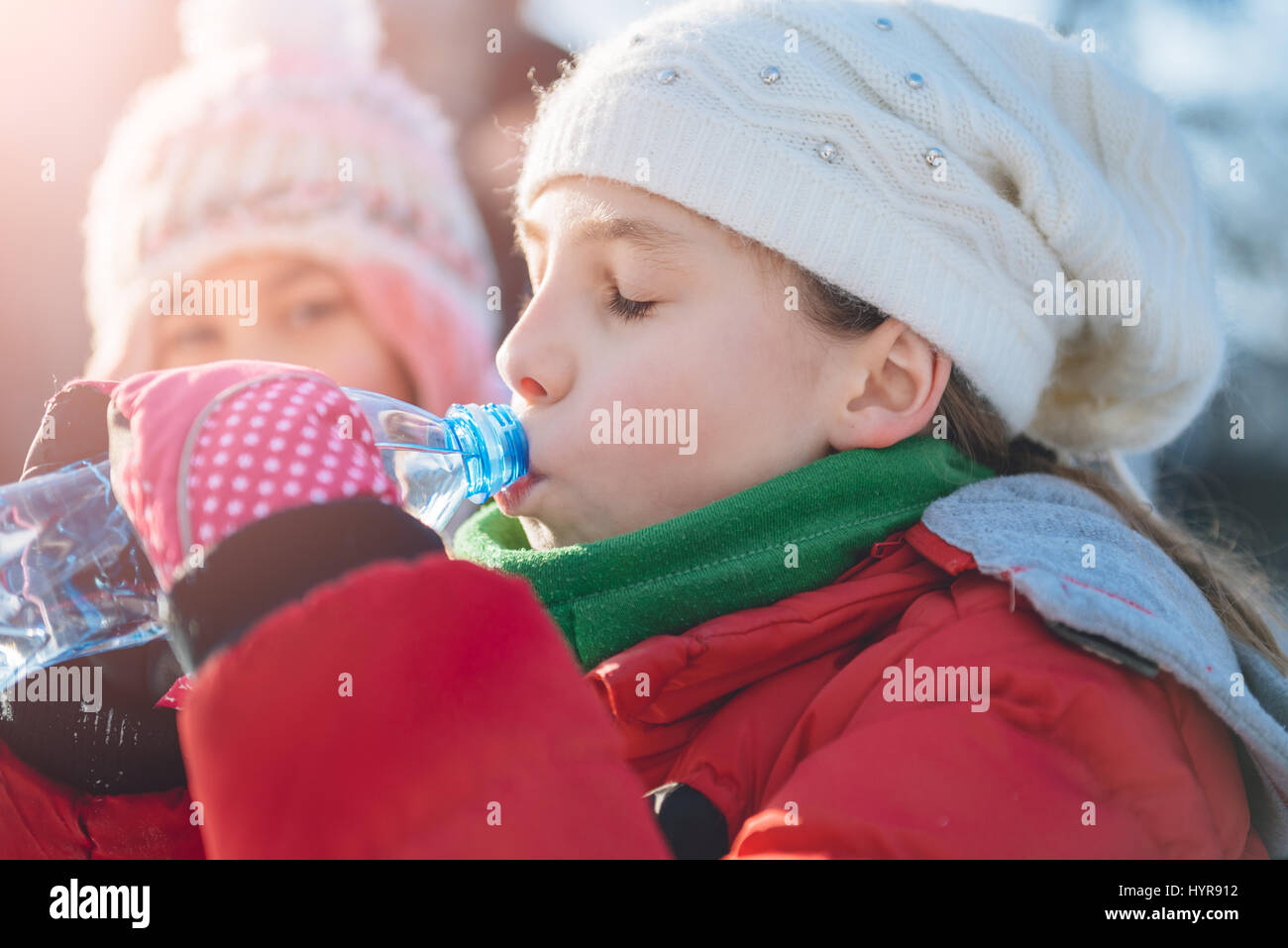 Ragazza indossando inverno cappello e giacca rossa acqua potabile per esterno Foto Stock