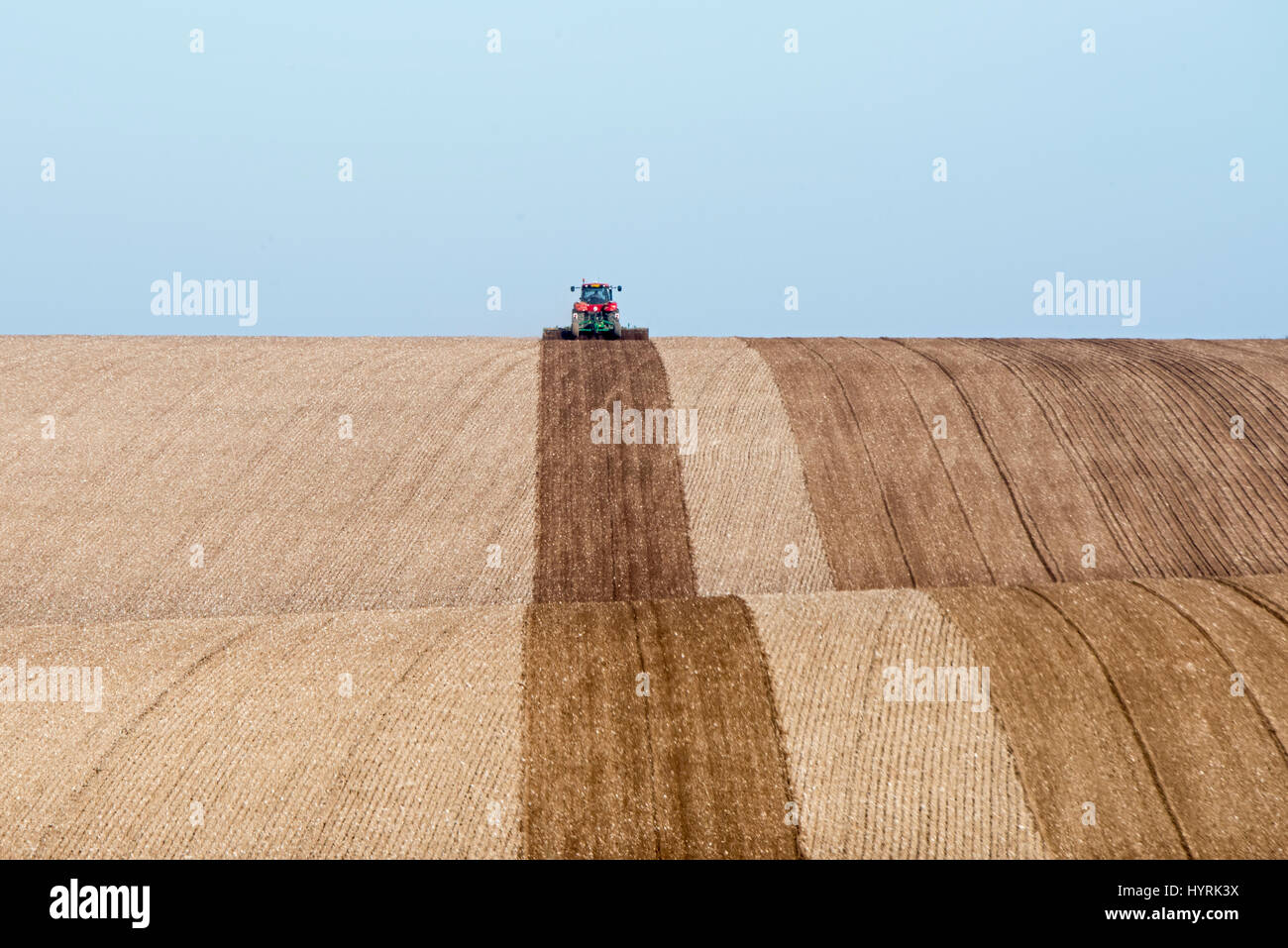 Il trattore di rotolamento di aratura terreni agricoli nei pressi di Docking North Norfolk Marzo Foto Stock