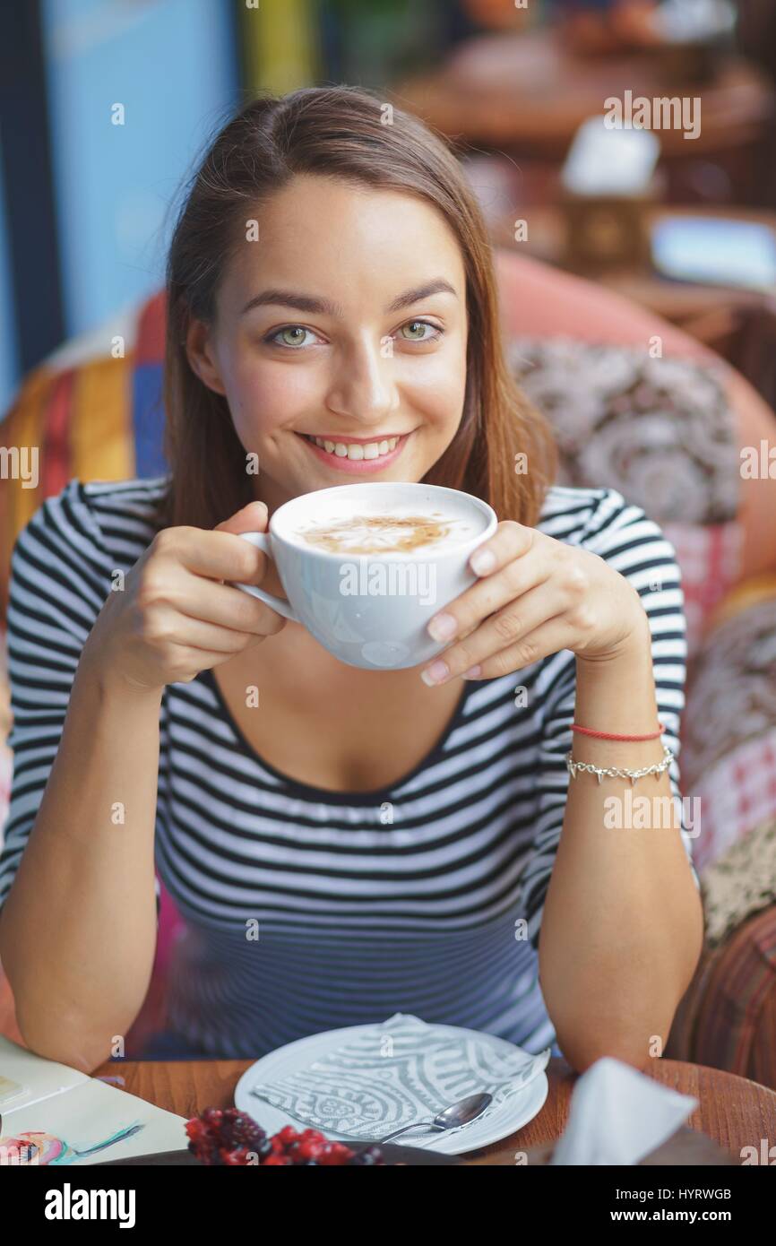 Giovane donna seduta indoor in ambiente urbano cafe. Cafe lo stile di vita della città. Casual ritratto della ragazza adolescente Foto Stock