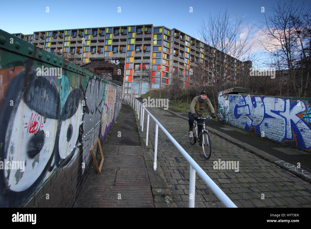 Uomo in bicicletta da Park Hill Station wagon di alloggiamento, un brutalist landmark sulla città di Sheffield sullo skyline e la più grande struttura elencati in Europa Foto Stock