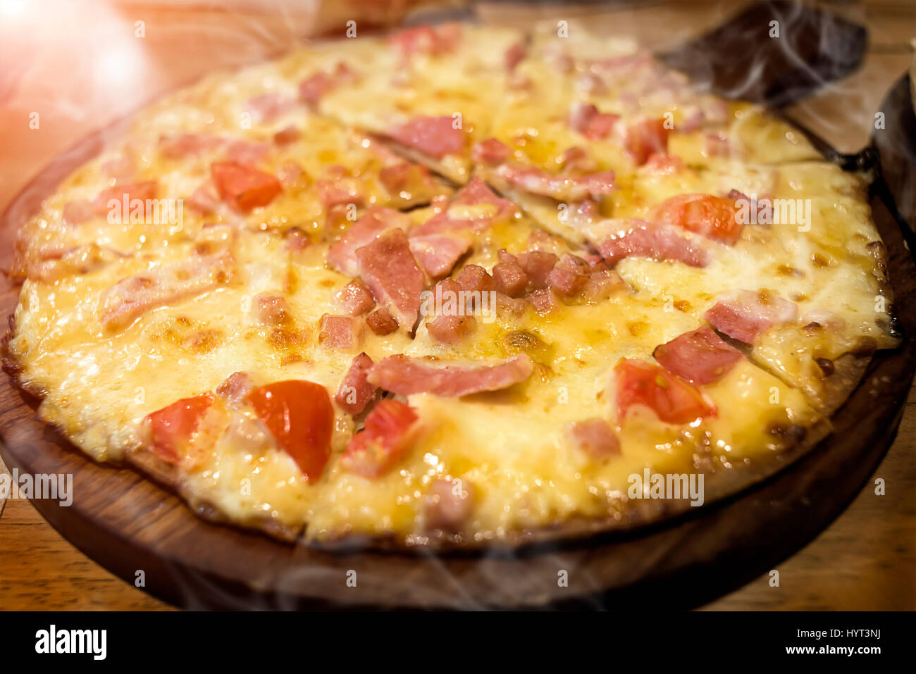 Home pizza fatta di prosciutto e formaggio a caldo e il fumo sul servire foto in interni molto bassa illuminazione . Foto Stock