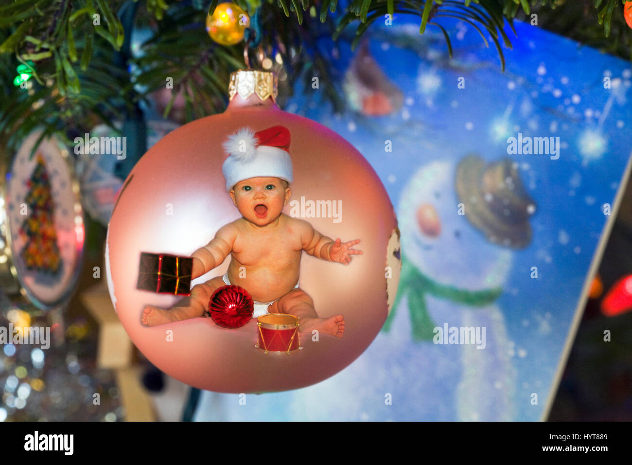 Un bambino che indossa un berretto di babbo natale su un albero di Natale ornamento, appeso a un albero di Natale. Foto Stock