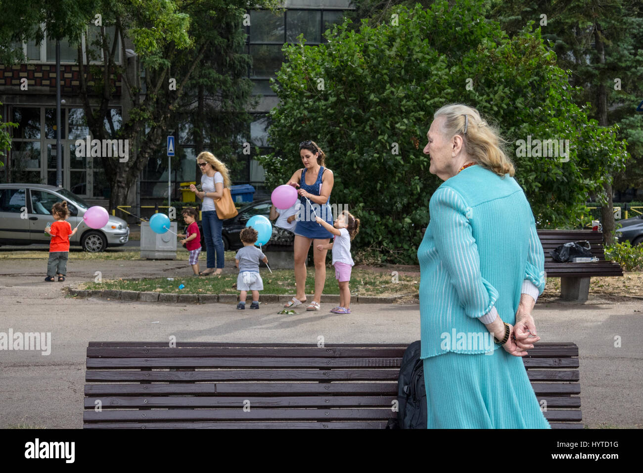 Belgrado, Serbia - Agosto 2, 2015: vecchia donna guardando le donne più giovani di prendersi cura di bambini che giocano con palloncini nel quartiere di Zemun P Foto Stock