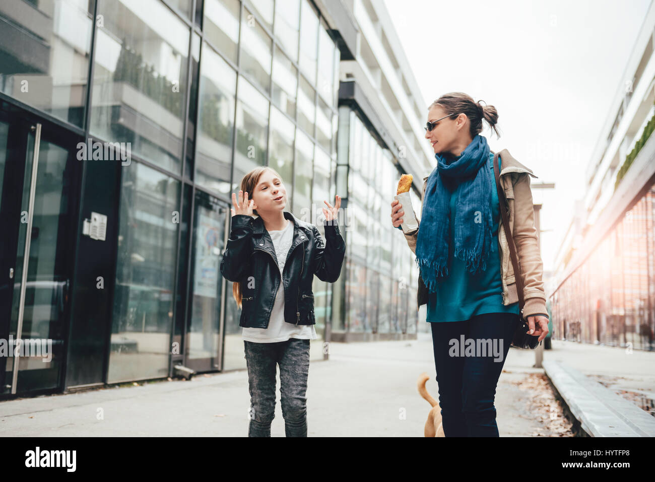 Madre e figlia passeggiando per le strade della città e mangiare panino Foto Stock