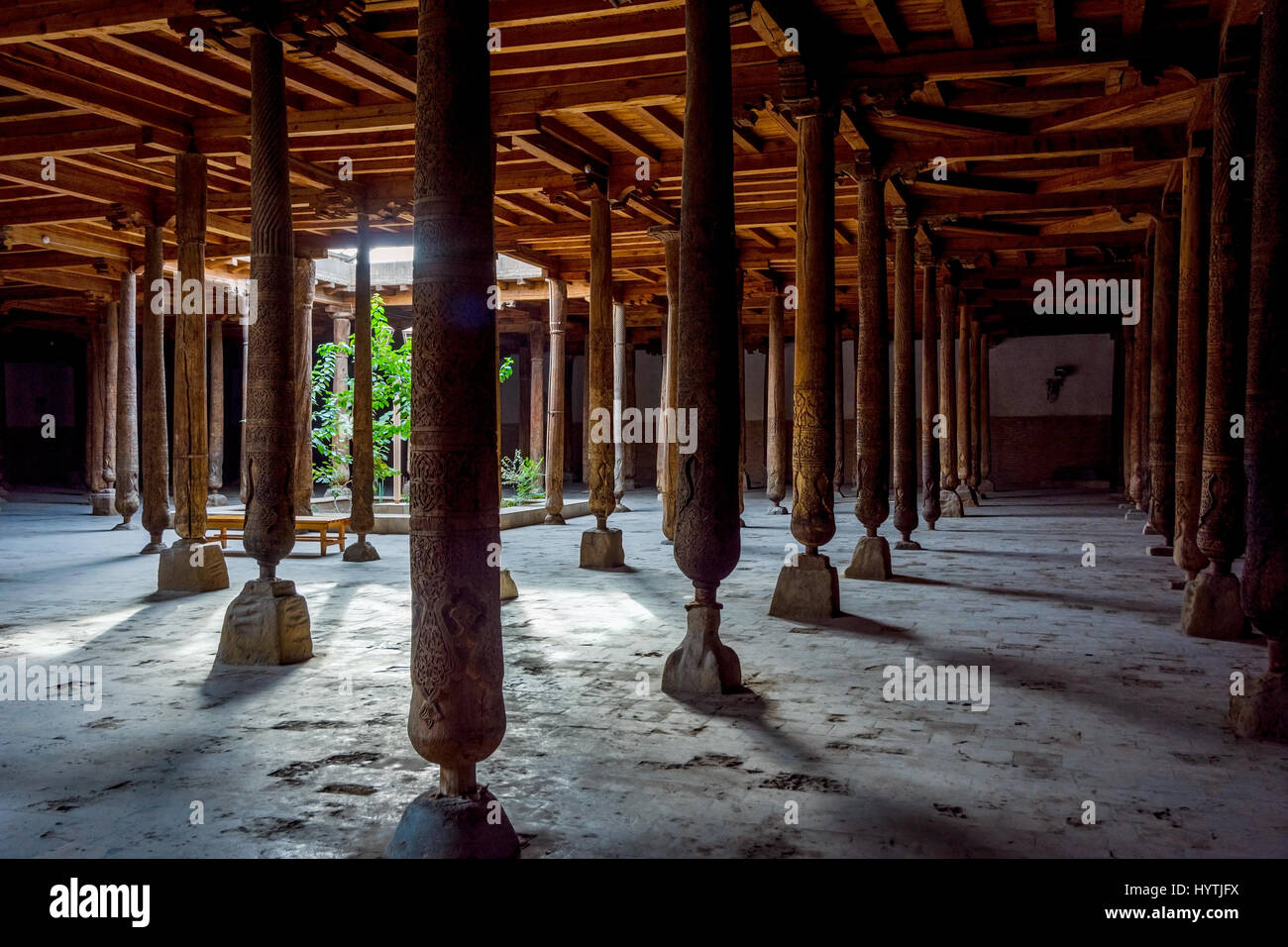 Raggi di sole che splende attraverso molti in legno intagliato pilastri nella vecchia madrassa di Khiva, Uzbekistan Foto Stock