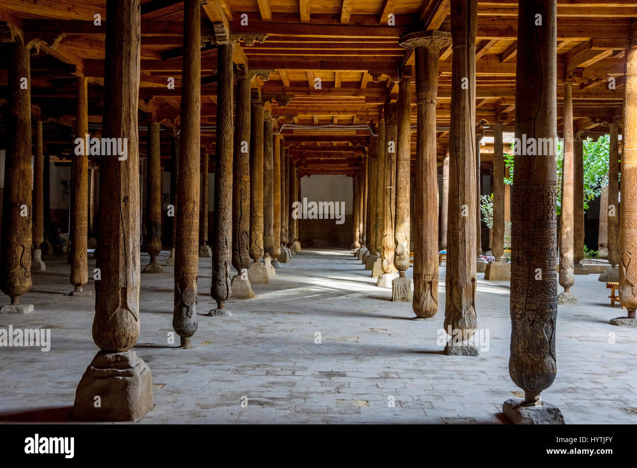 Raggi di sole che splende attraverso molti in legno intagliato pilastri nella vecchia madrassa di Khiva, Uzbekistan Foto Stock