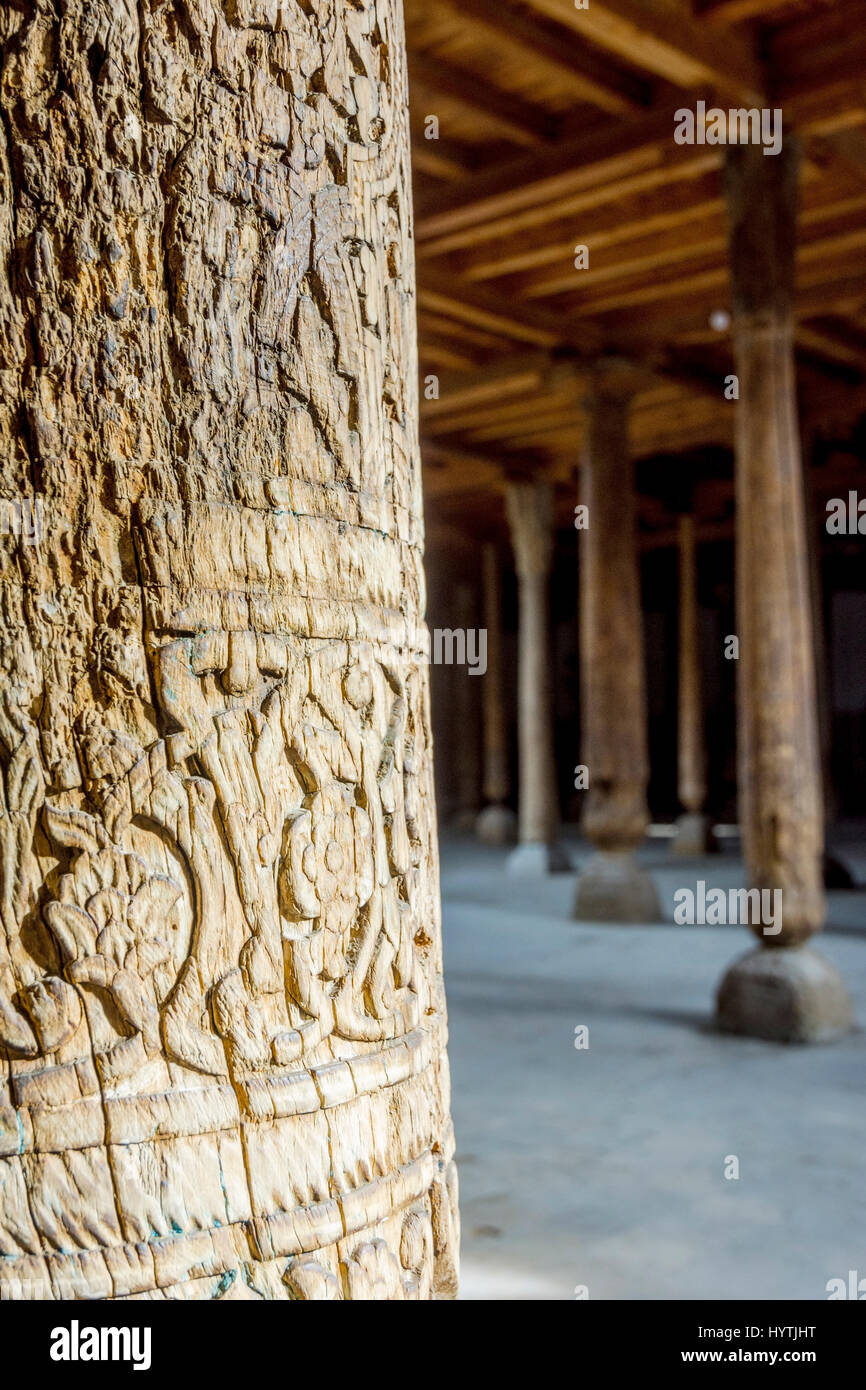 Raggi di sole che splende attraverso molti in legno intagliato pilastri nella vecchia madrassa di Khiva, Uzbekistan Foto Stock