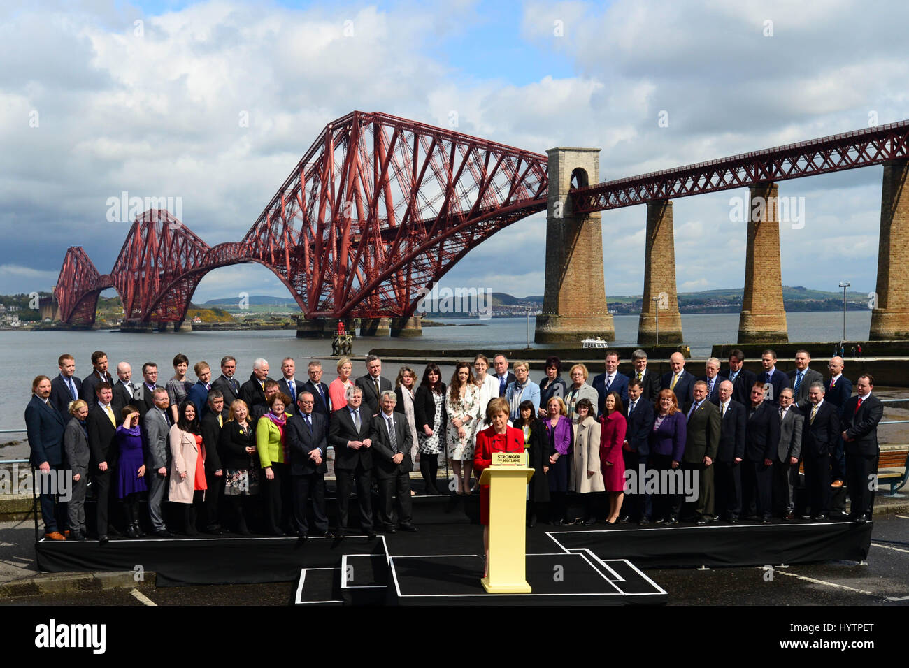 SNP leader scozzese e primo ministro Nicola Storione dà un discorso circondato dal gruppo di 56 neo-eletto SNP MPs, con la mitica Forth Bridge in background Foto Stock