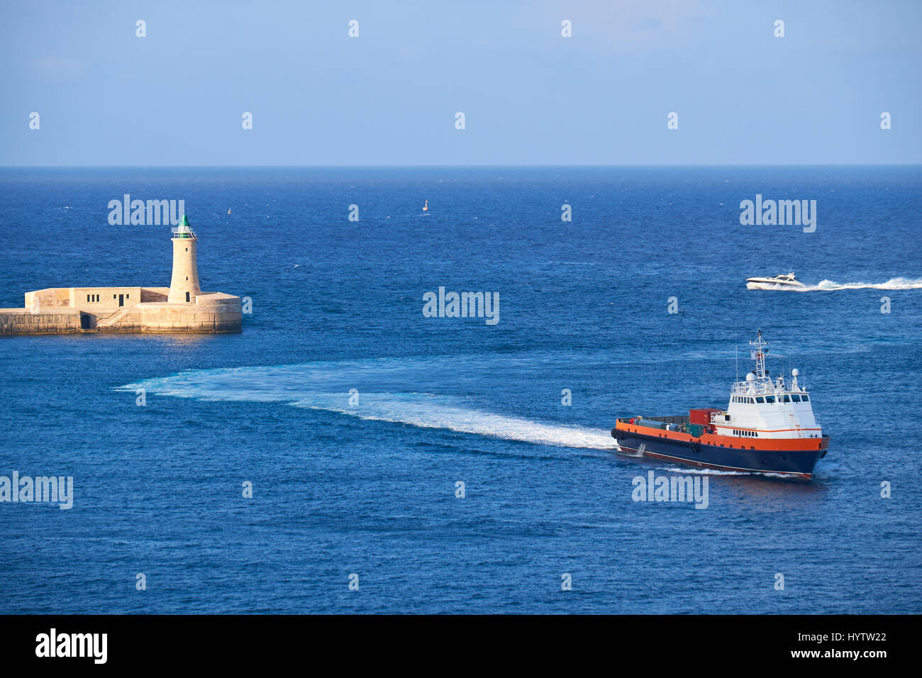 Una barca a motore entra al Grand Harbour (porto di La Valletta) vicino al Saint Elmo Faro. Foto Stock