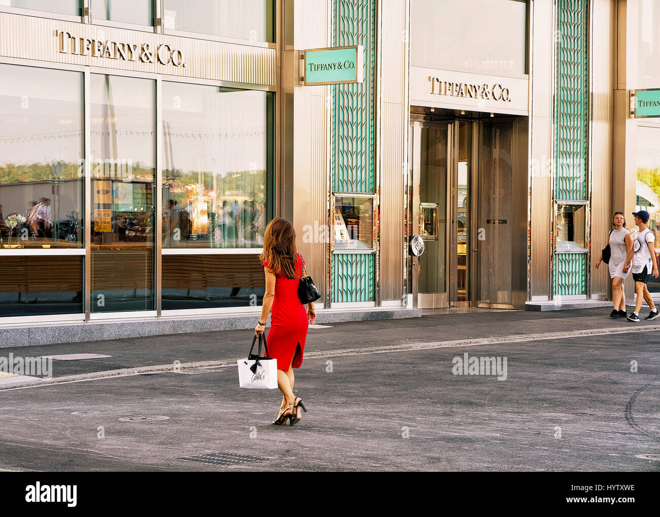 Ginevra, Svizzera - 30 agosto 2016: Donna in abito rosso andando a Tiffany negozio gioielli nel centro di Ginevra, Svizzera Foto Stock