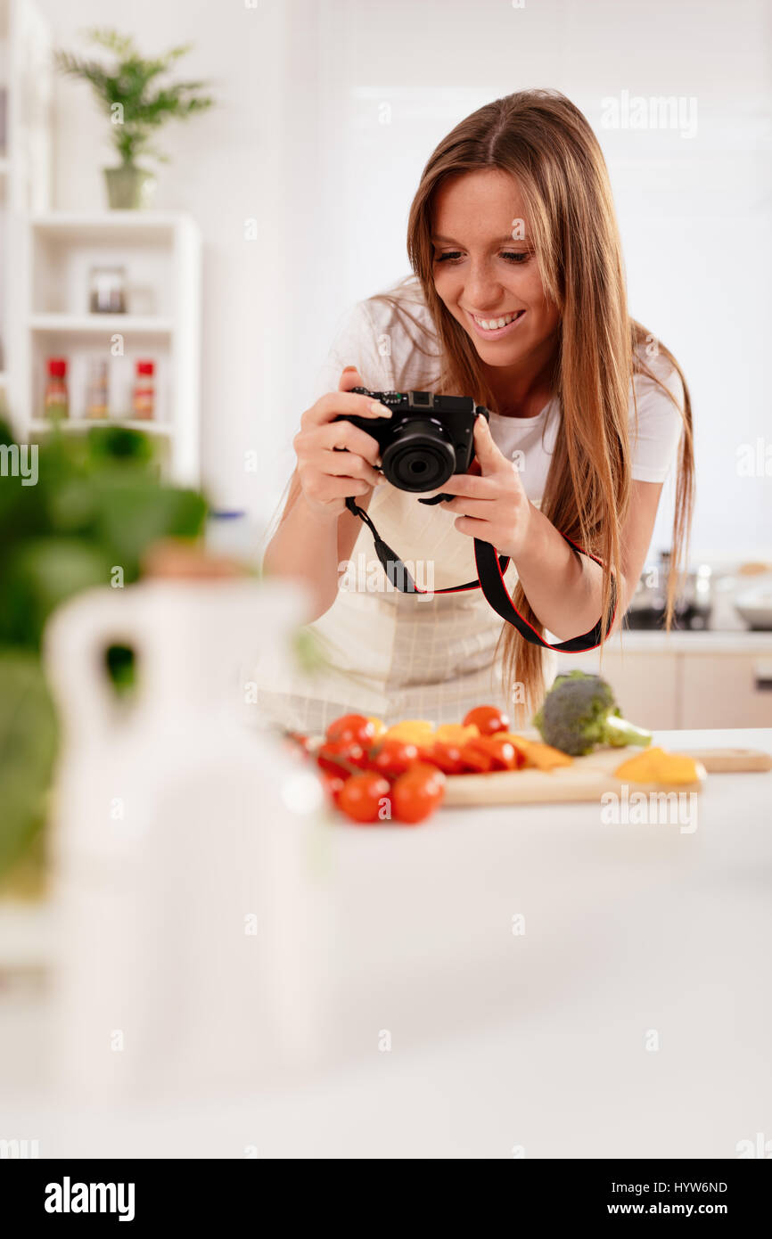 Bella giovane donna prendendo la foto di una sana insalata con fotocamera digitale per il suo blog. Foto Stock