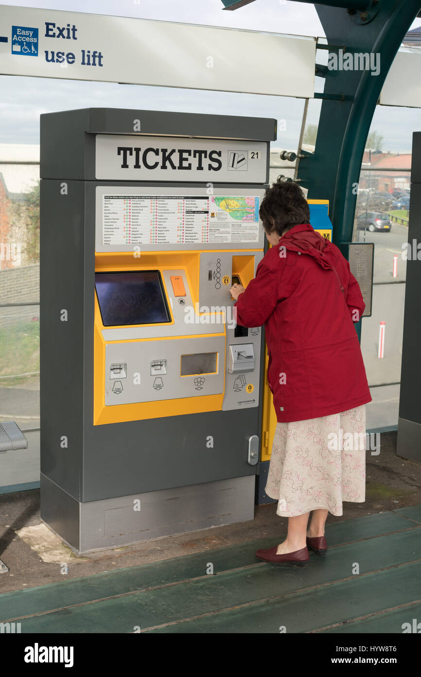 Donna di comprare un biglietto da un distributore automatico sul Tyneside Metro, England, Regno Unito Foto Stock