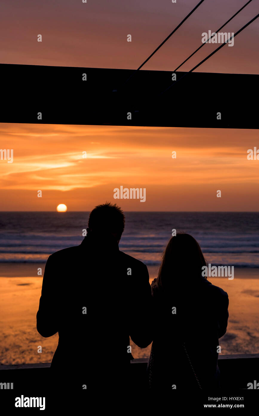 Sunset Silhouette di gente giovane vicino al mare sulla costa del sole Fistral Beach fine della sera del giorno del tramonto Oceano Mare Tempo libero Turismo Foto Stock