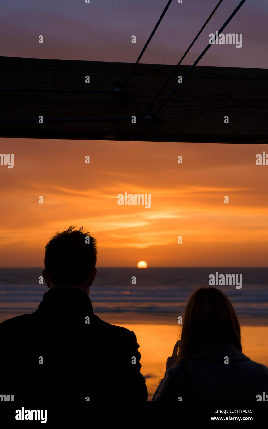 Sunset Silhouette di gente giovane vicino al mare sulla costa del sole Fistral Beach fine della sera del giorno del tramonto Oceano Mare Tempo libero Turismo Foto Stock