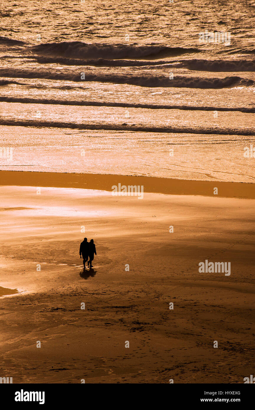 Paio di persone a piedi Silhouette Fistral Beach Sunset serata romantica fine della giornata a riva litorale Newquay Cornwall Foto Stock