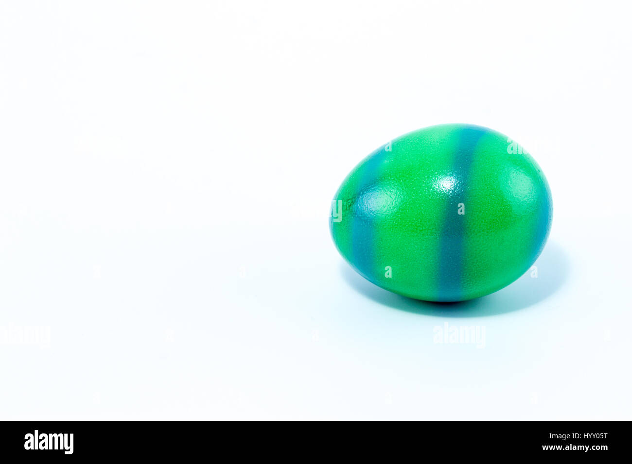 Uova pasquali dipinte a mano in home - verde con strisce blu, isolato in uno sfondo bianco Foto Stock