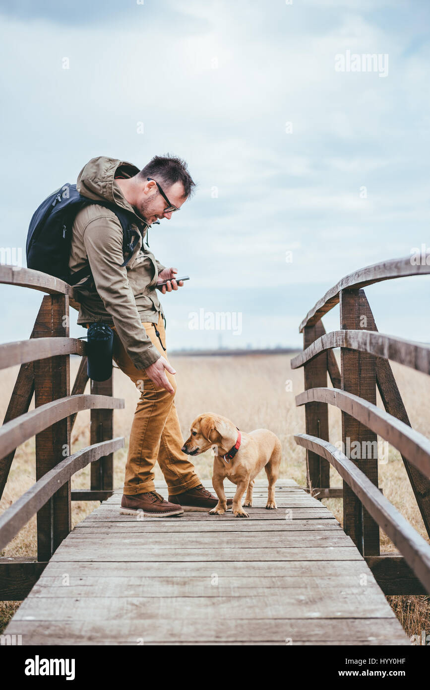 Escursionista petting un cane su un ponte di legno Foto Stock