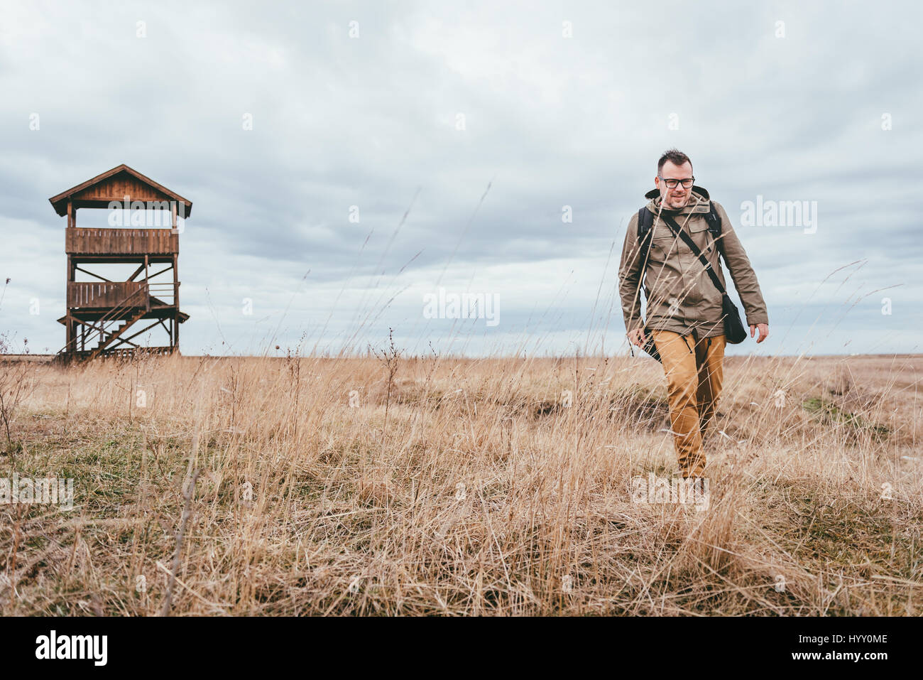 Escursionista camminando su prati dietro la sua è una cabina di riposo Foto Stock