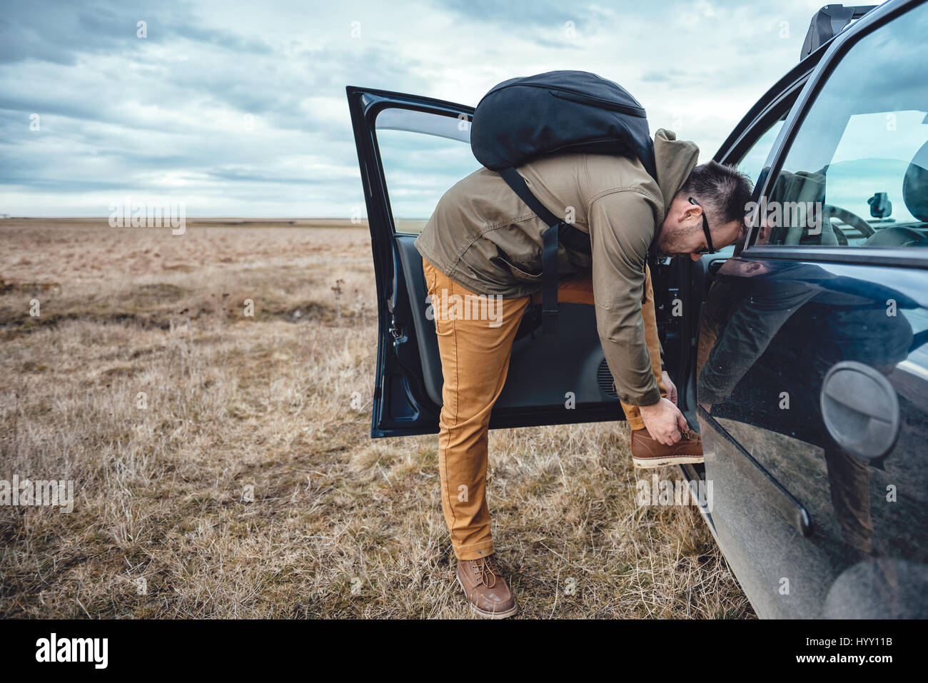 Escursionista in piedi dalla vettura e legando i lacci delle scarpe Foto Stock