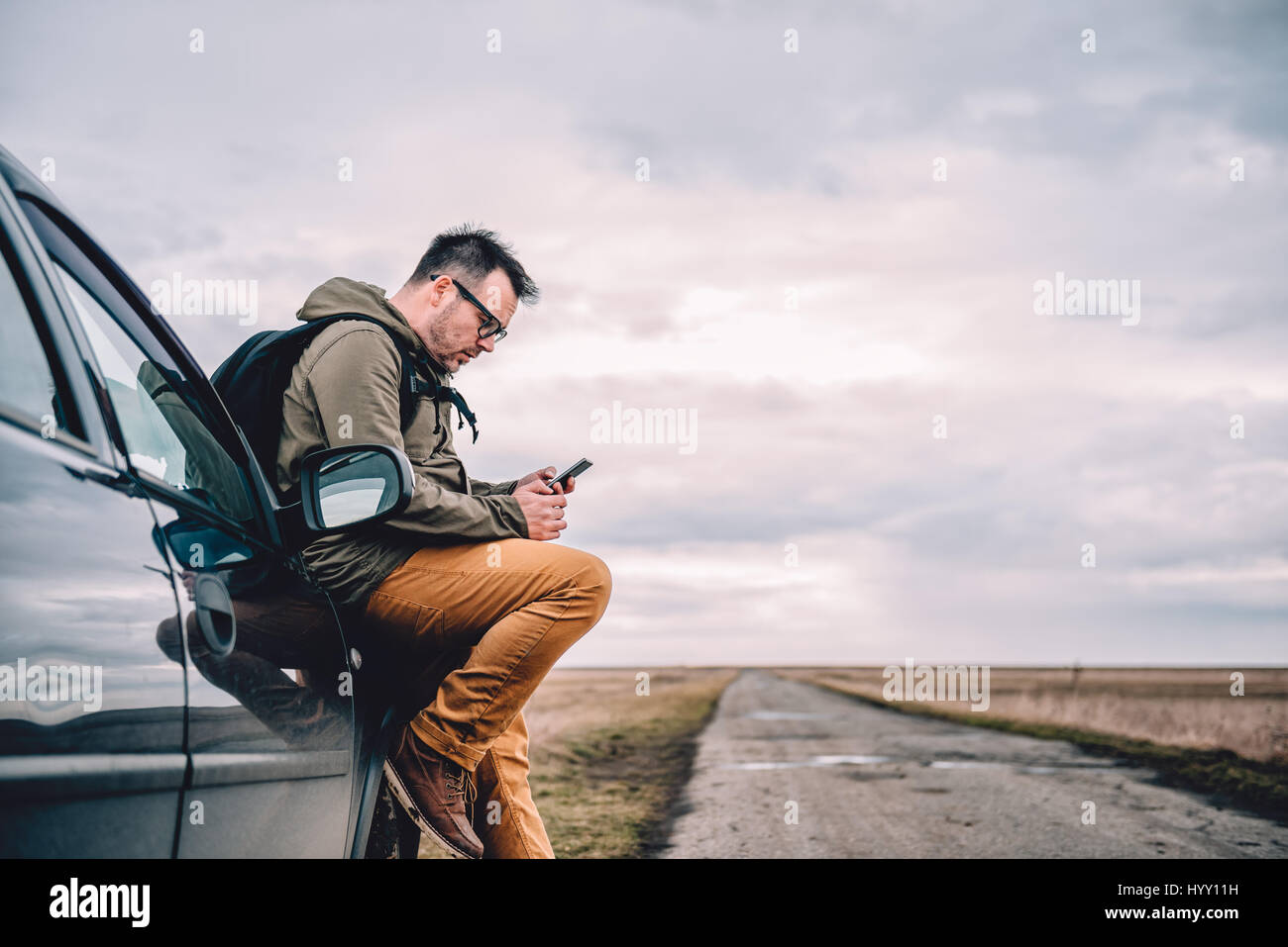 Uomo seduto sulla vettura e utilizzo di smart phone Foto Stock