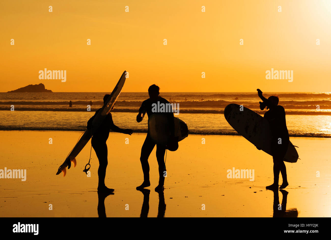 3 surfers su Fistral Beach al tramonto in Newquay, Cornwall, Regno Unito Foto Stock