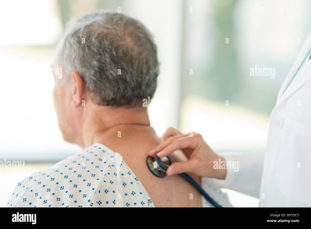 Medico donna utilizzando uno stetoscopio sul paziente di sesso maschile. Foto Stock