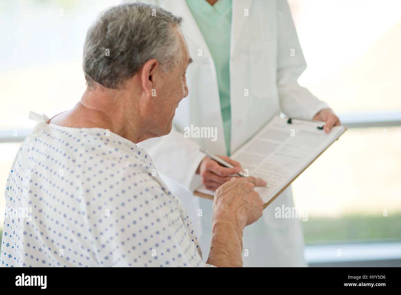 Senior uomo rivolto a Note mediche in ospedale. Foto Stock