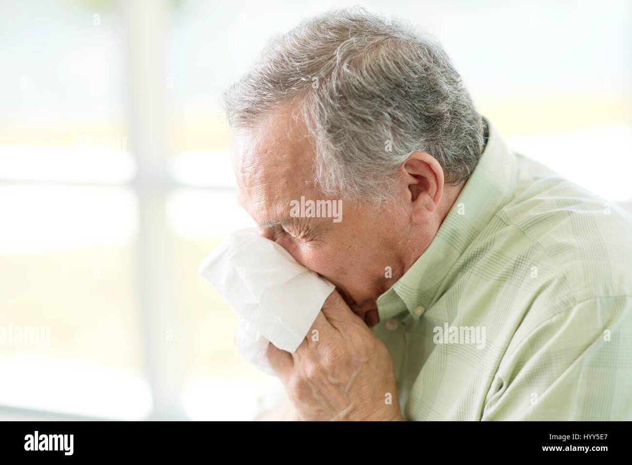 Senior uomo soffia il naso sul tessuto. Foto Stock