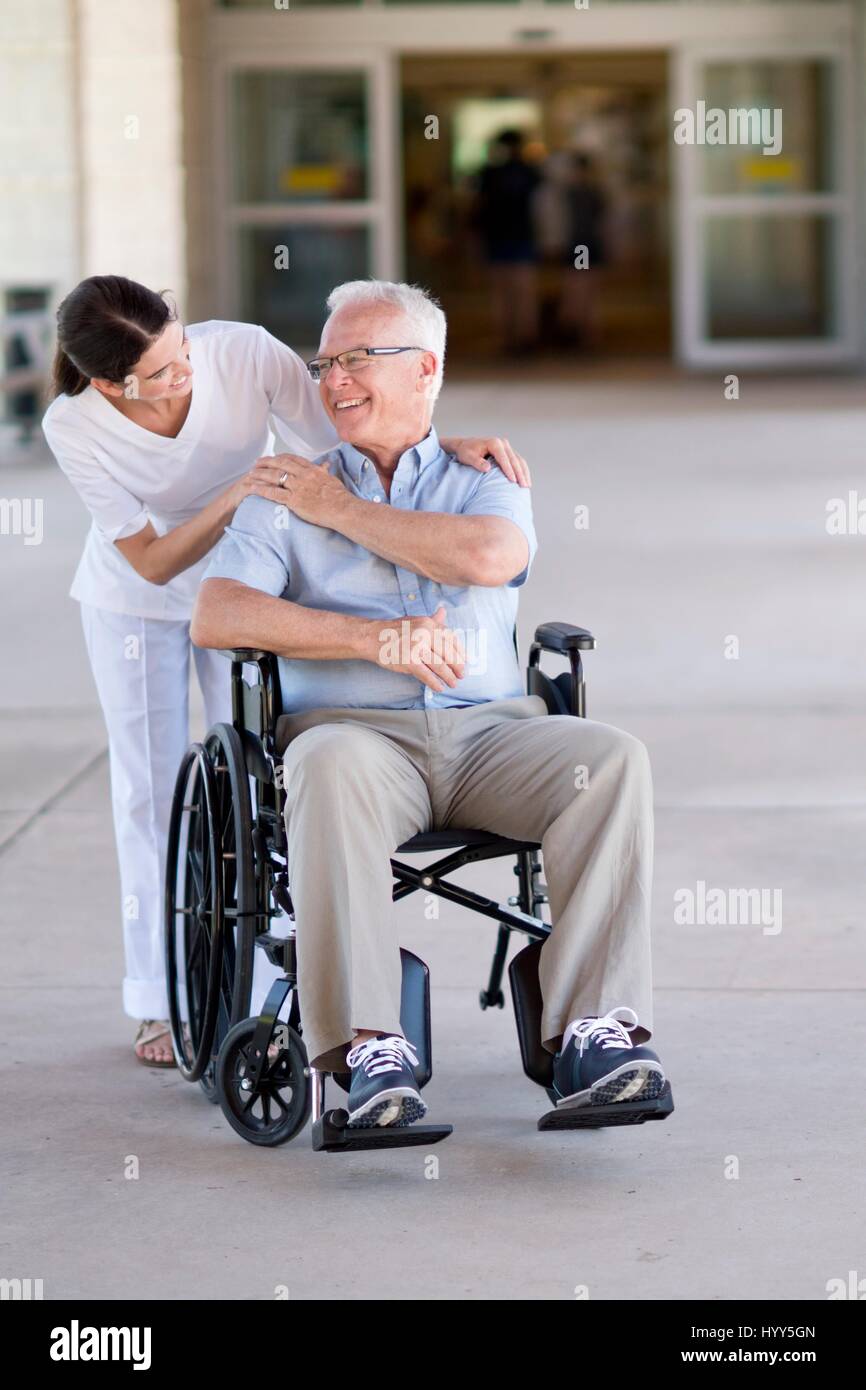 Senior uomo in sedia a rotelle con cura lavoratore. Foto Stock