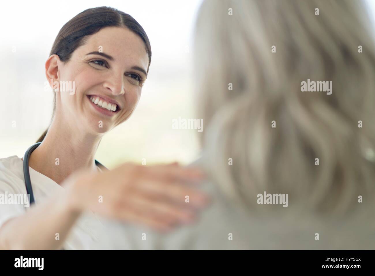 Femmina lavoratore cura sorridente verso il paziente. Foto Stock